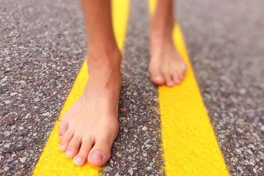 A man walks barefoot down a road